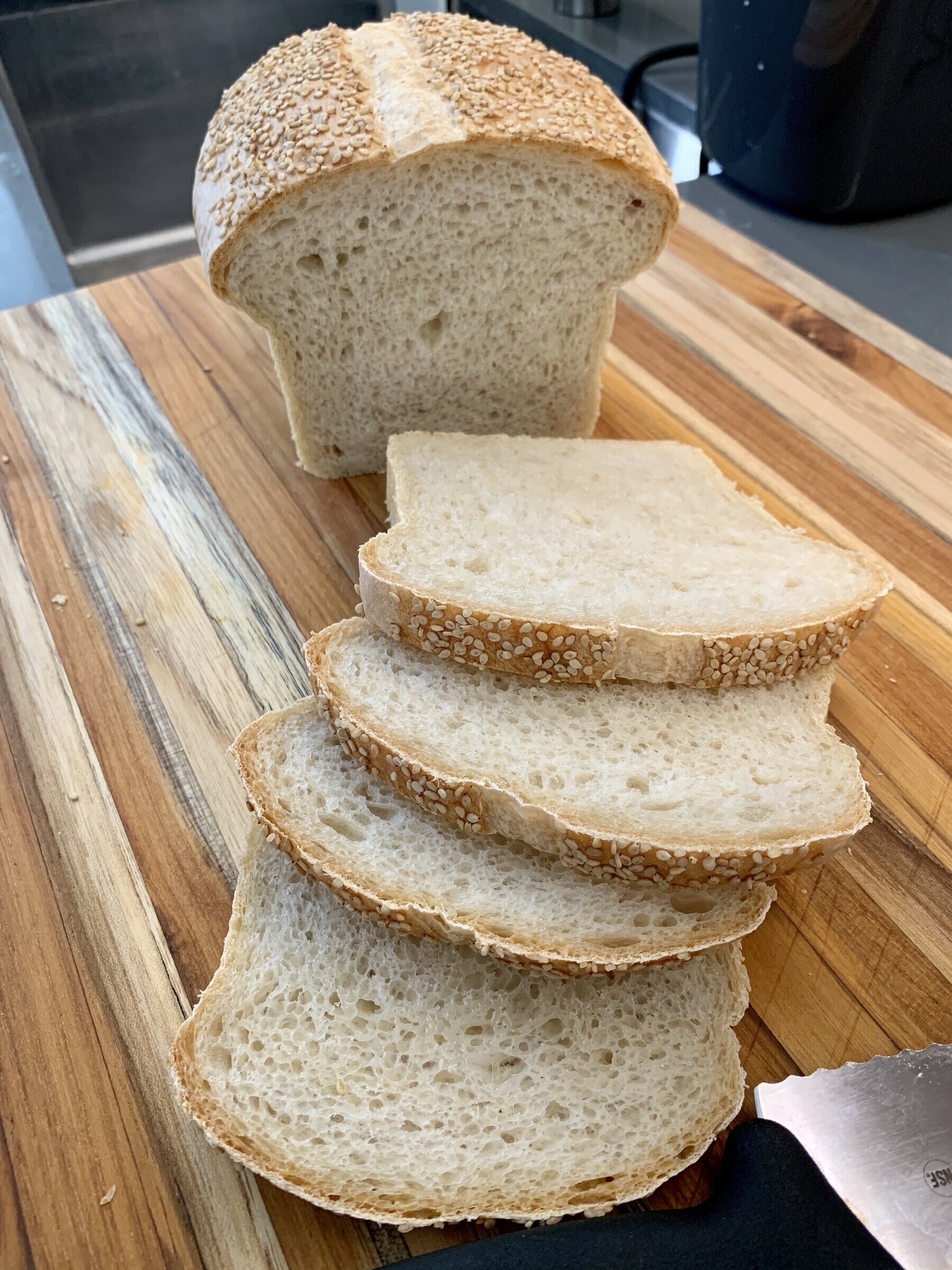 Loaf of sesame sourdough sandwich bread, partly sliced